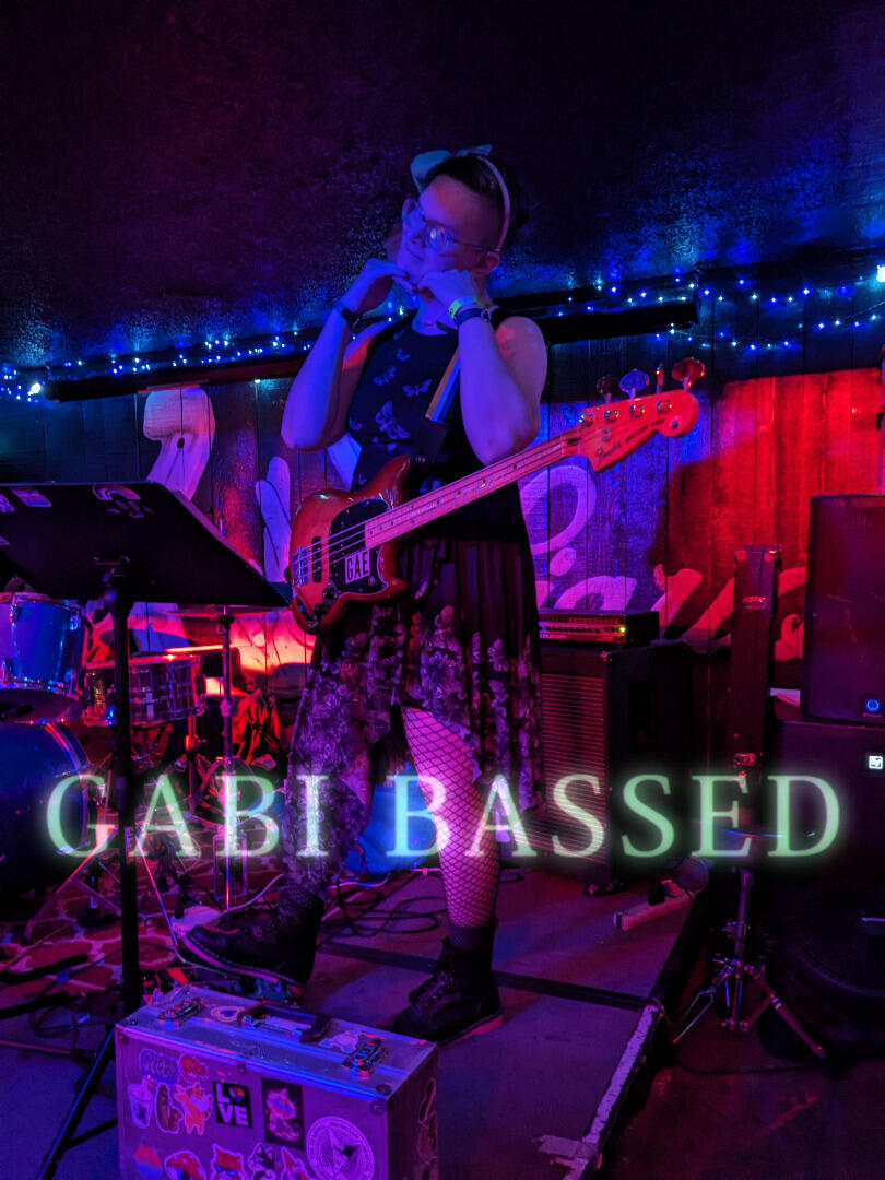 Gabi making a cute pose while sustaining an open note on faer bass in between songs